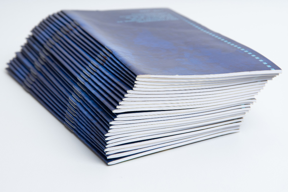 Stack of blue notebooks with white pages.