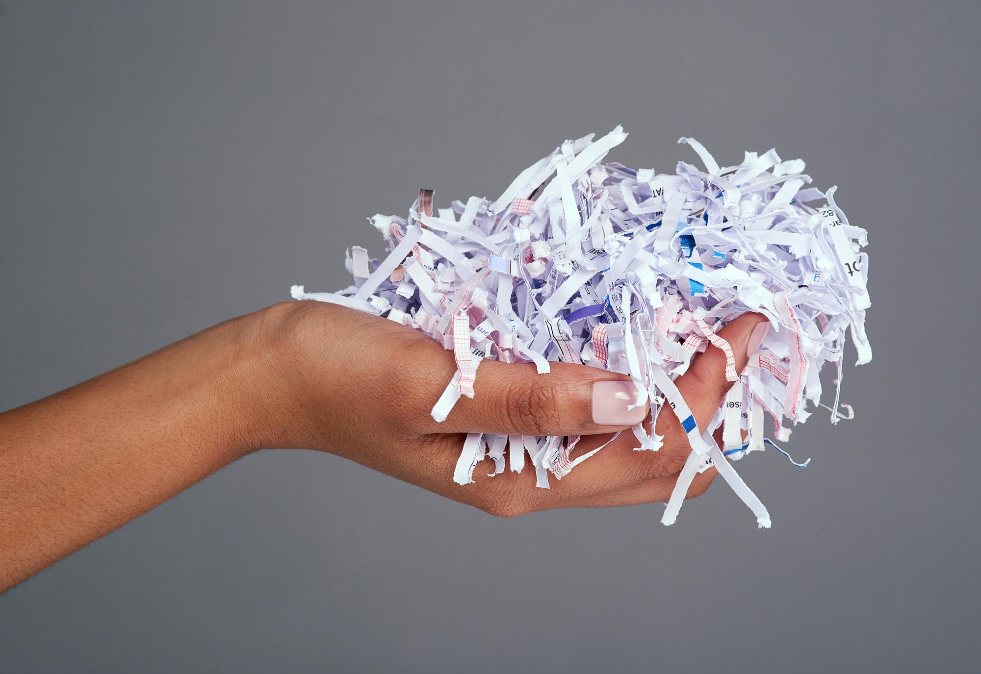 protect-your-information-studio-shot-womans-hand-holding-pile-shredded-paper-against-grey-background
