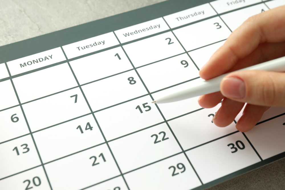 Person marking a date on calendar with pen.