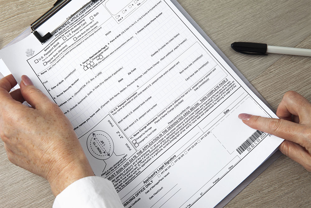 female hand pointing out a form indicating assistance to fill out the form on a clipboard with a pen laying down on the side
