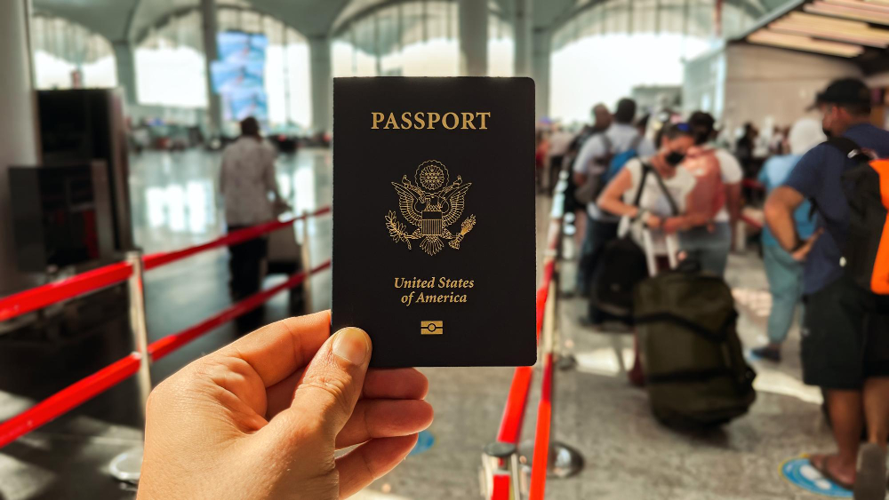 holding-blue-american-passport-international-airport-touirists-are-blurred-background